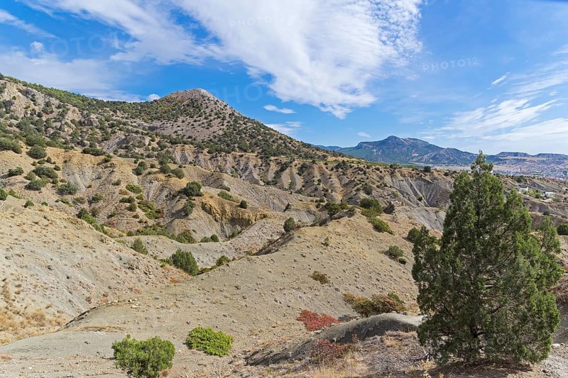 Clay ravines at the foot of the mountains. On the slopes of ravines one can see the structure of sedimentary rocks. Crimea, sunny day in September