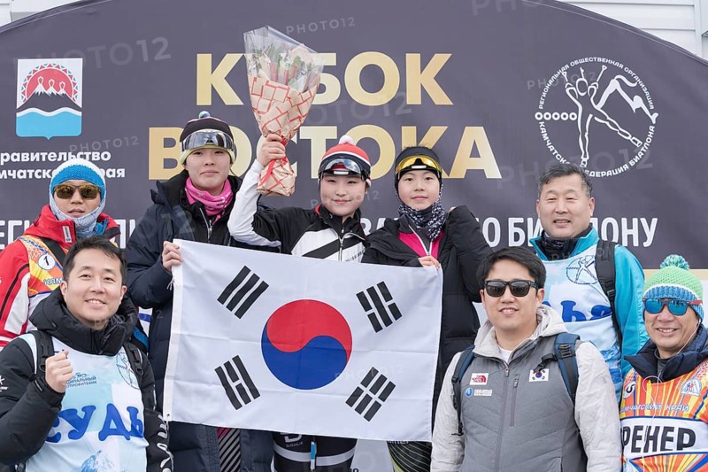 Korean team of sportswoman biathletes, coaches and sports judges with national flag of South Korea during award ceremony. Junior biathlon competitions East of Cup. Kamchatka, Russia, April 12, 2019, Europe