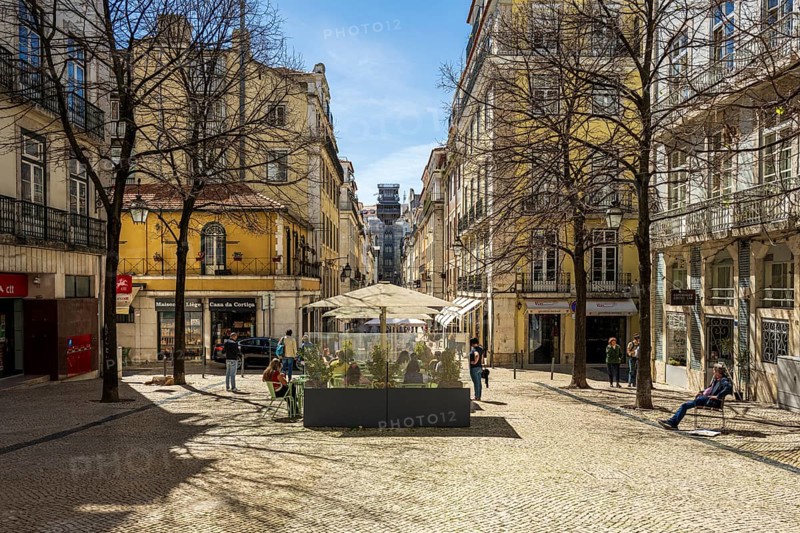 View through the streets to the Elevador de Santa Justa in Lisbon, a sunny city square with historic buildings and a lively street café in the centre. People going for a walk, Lisbon, Portugal, Europe