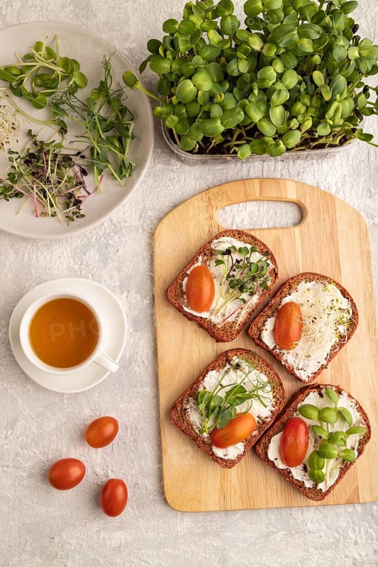 Red beet bread sandwiches with cream cheese, tomatoes and microgreen on gray concrete background. top view, flat lay, close up