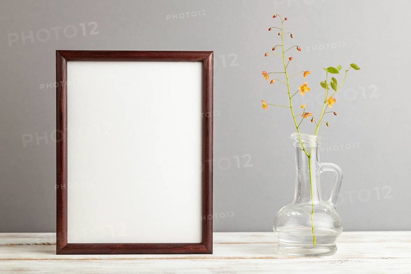 Wooden frame with orange barrenwort flowers in glass on gray pastel background. side view, copy space, still life, mockup, template, spring, summer minimalism concept