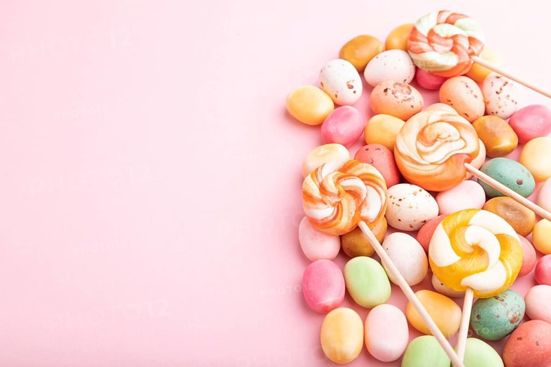 Various caramel candies on pink pastel background. copy space, side view