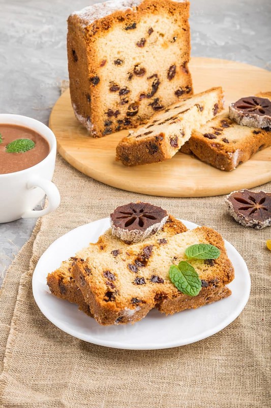 Homemade cake with raisins, dried persimmon and a cup of hot chocolate on a gray concrete background and linen textile. Side view, close up