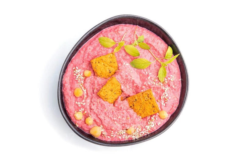 Hummus with beet and microgreen basil sprouts in ceramic bowl isolated on white background. Top view, close up