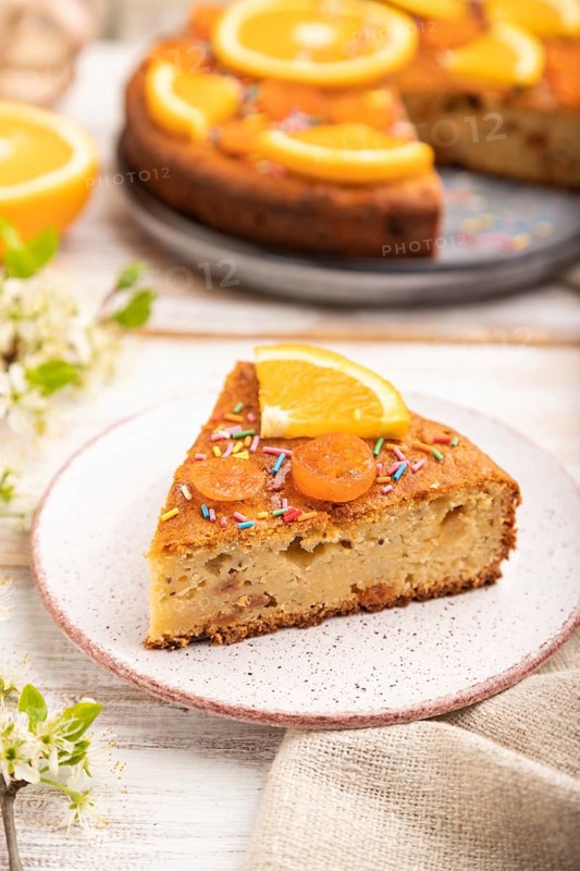 Orange cake and a cup of coffee on a white wooden background and linen textile. Side view, close up, selective focus