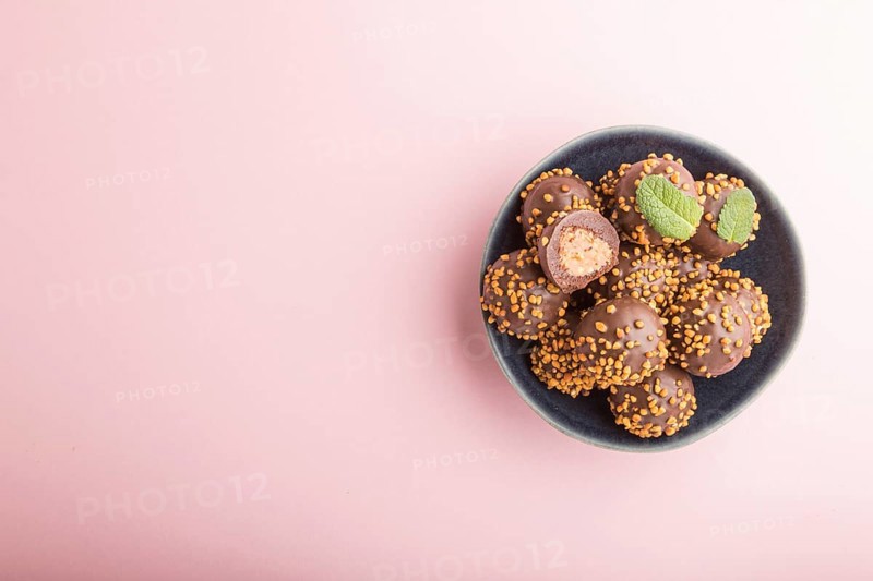Chocolate caramel ball candies with almonds on a pastel pink background. top view, flat lay, copy space