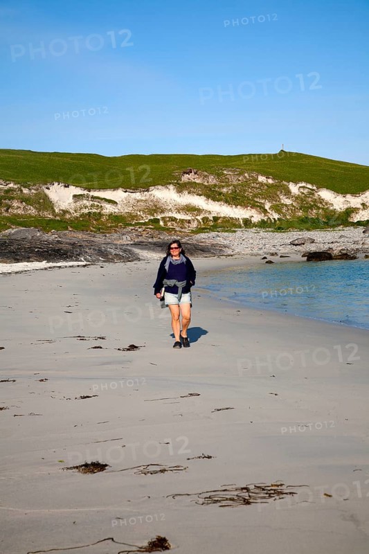 Woman walking on sandy beach at Bagh a Deas, South Bay, Vatersay island, Barra, Outer Hebrides, Scotland, UK