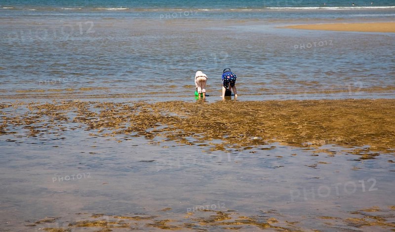 Two children playing with buckets in the sea at Hunstanton, north Norfolk coast, England, United Kingdom, Europe