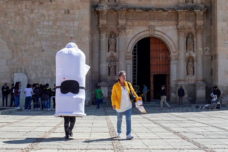 Oaxaca, Mexico, A person wearing a condom costume walks with a health worker handing out free condoms as part of a fight against sexually-transmitted diseases. Here they pass the Catholic cathedral, Templo de Santo Domingo Guzman. Catholics are forbidden to use condoms for contraception, but may use them to prevent disease, Central America