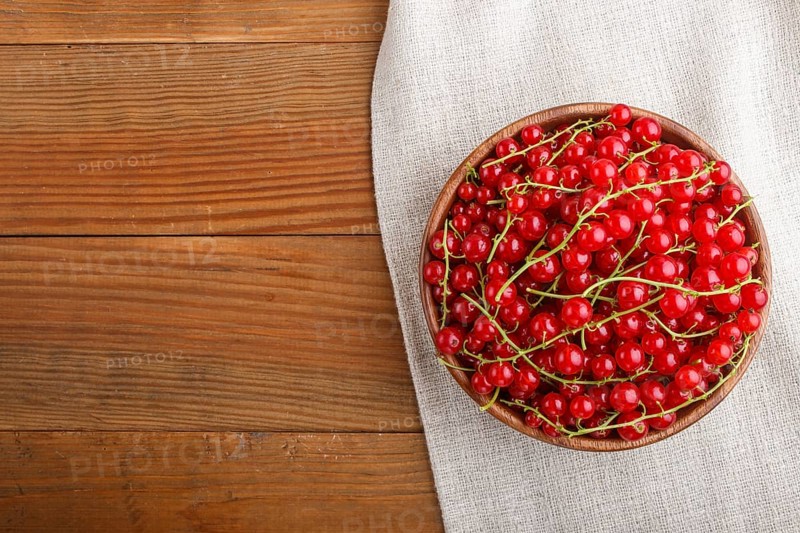 Fresh red currant in wooden bowl on wooden background. top view, flat lay, copy space
