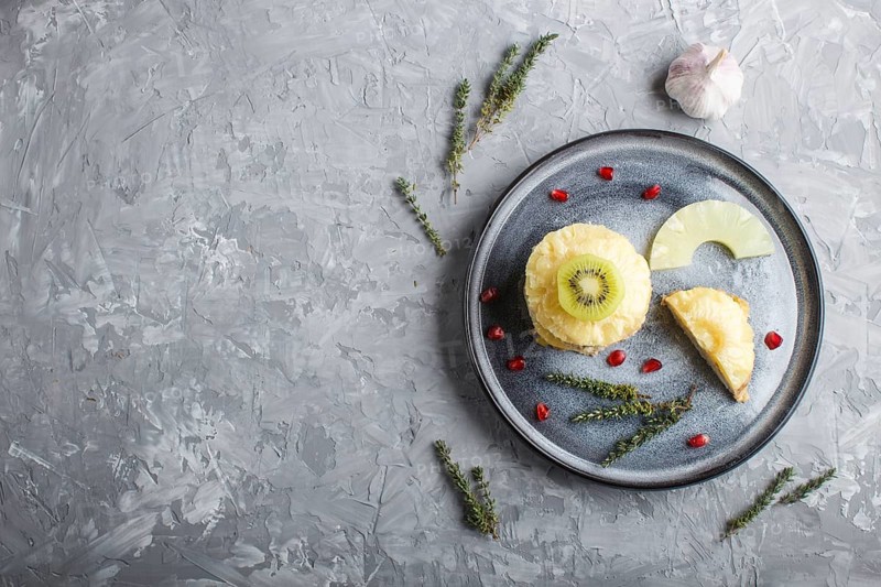 Pieces of baked pork with pineapple, cheese and kiwi on gray plate, side view, close up, top view, flat lay, copy space
