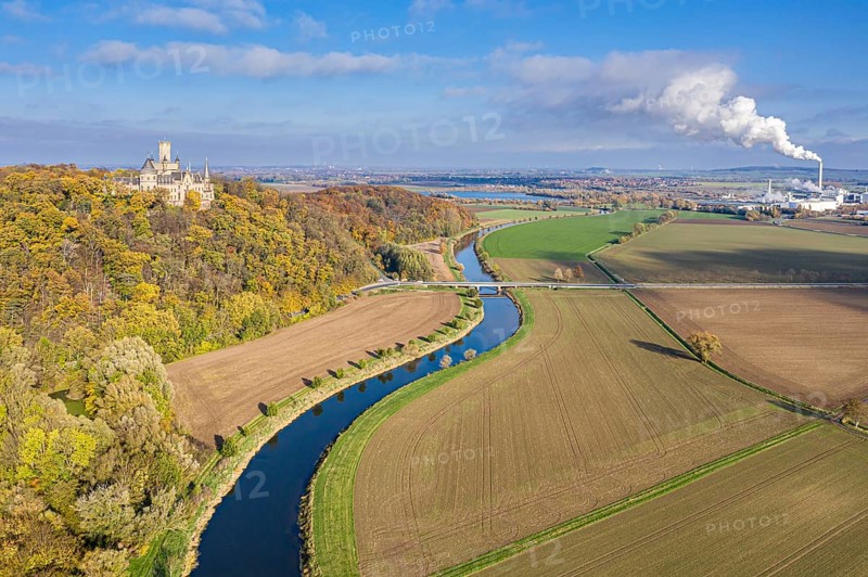 Castle Marienburg south from Hannover, on Mt Marienberg above river Leine, autumnal foliage, smoking chimneys of sugar factory Nordzucker in Nordstemmen, Germany, Europe