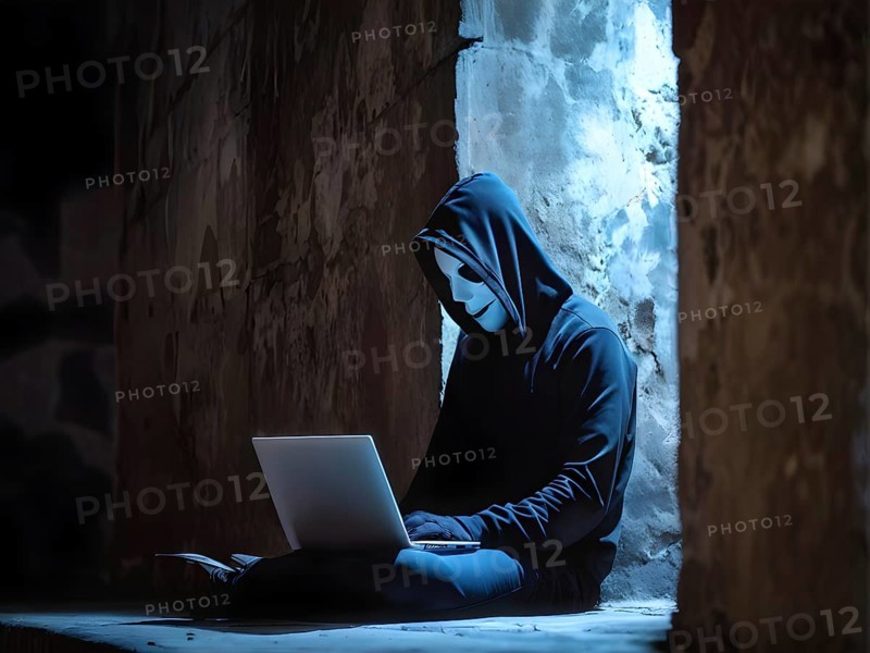 AI generated hooded man clutching a laptop symbolizing cyber criminality