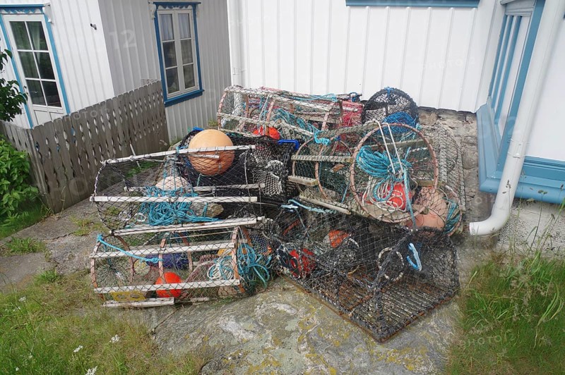Stacked fishing baskets and ropes next to a white house, the typical equipment for the fishing trade