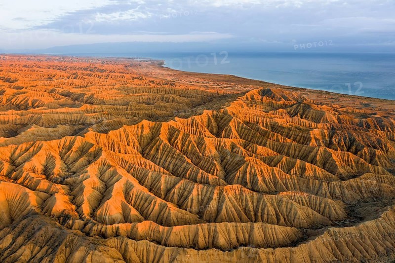 Landscape of eroded hills, badlands at sunset, Lake Issyk Kul in the background, aerial view, Canyon of the Forgotten Rivers, Issyk Kul, Kyrgyzstan, Asia