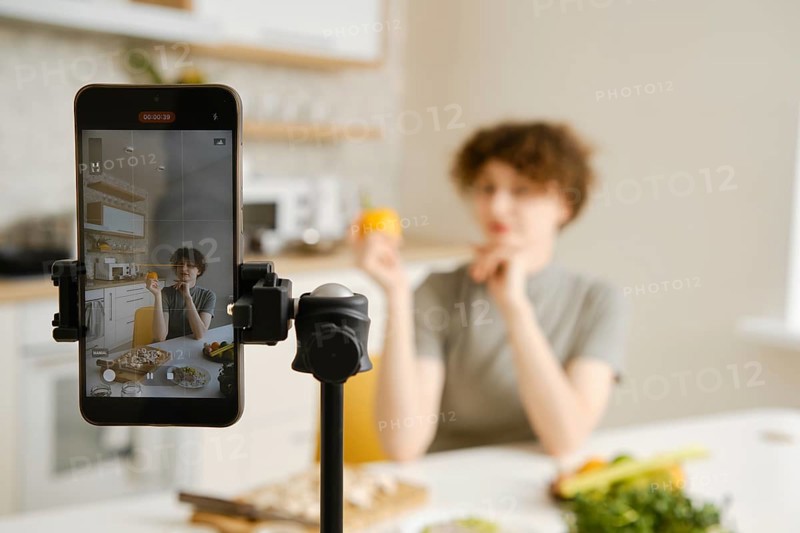 Professional nutritionist filming on her smartphone tutorial about healthy eating on her kitchen