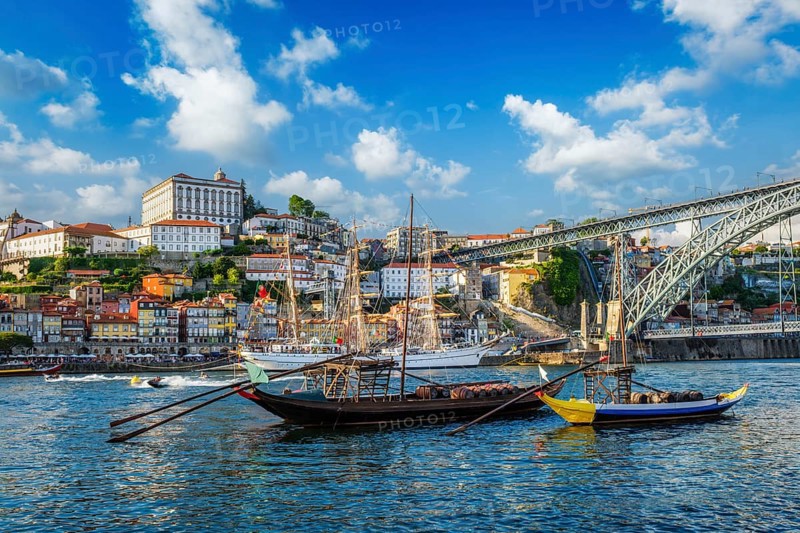 View of Porto city and Douro river with traditional boats with port wine barrels and sailing ship from famous tourist viewpoint Marginal de Gaia riverfront. Porto, Vila Nova de Gaia, Portugal, Europe