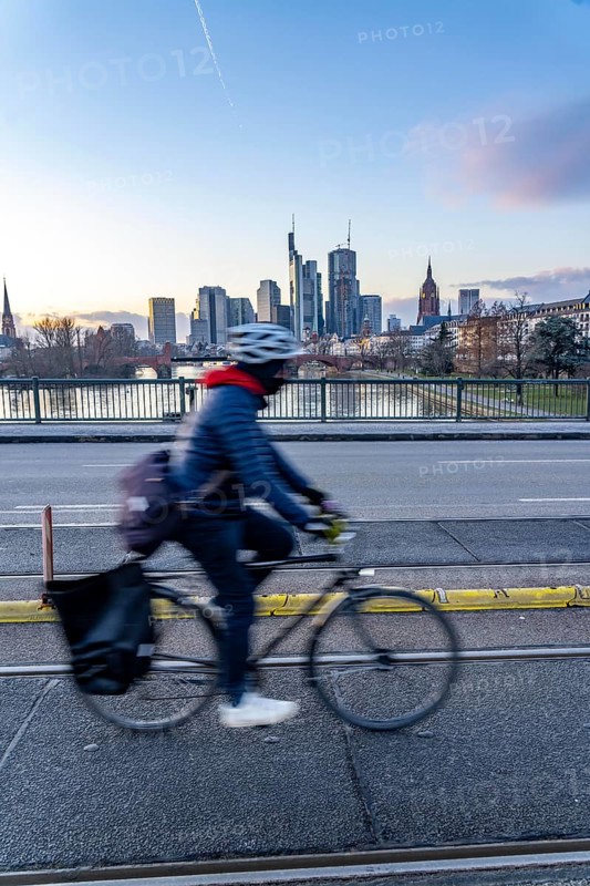 Skyline of the city centre of Frankfurt am Main, cyclist on the Ignatz-Bubis-Bridge, dusk, river Main, winter, Hesse, Germany, Europe