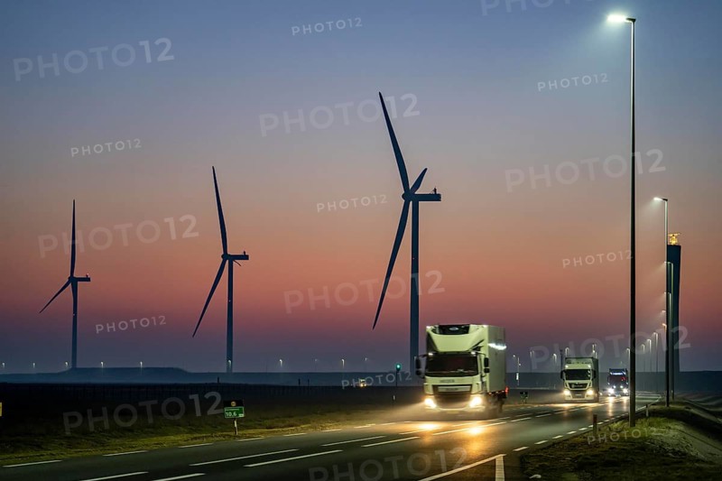 Lorry on the road to Euromax Terminal Rotterdam, ENECO wind farm on the dike around the port of Maasvlakte 2, 22 wind turbines with a capacity of 116 megawatts, sunset, Rotterdam, Netherlands