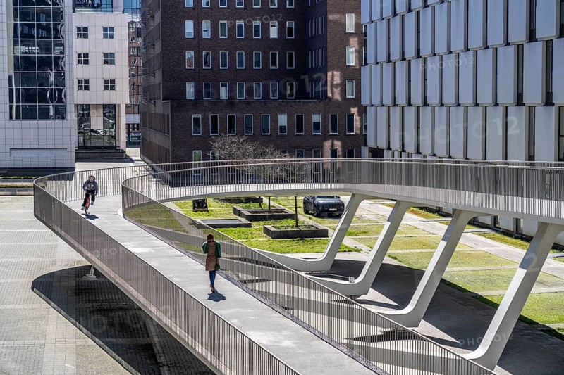 The Parkbruk, cycle and pedestrian bridge in the city centre of Antwerp, crosses a multi-lane city centre road with tram lines and thus connects two lively city districts Kop Spoor Noord and Eilandje, 140 metres of curved ramp on the western side for driving up and down, walking, Belgium, Europe