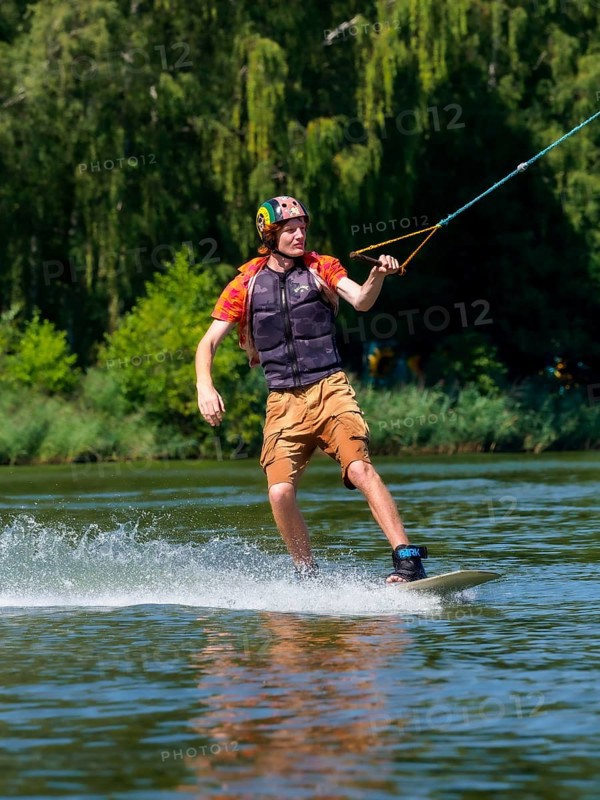 Young casual man with flapping shirt on wakeboard in lake, water ski and wakepark, Stráž pod Ralskem, Czech Republic, Europe