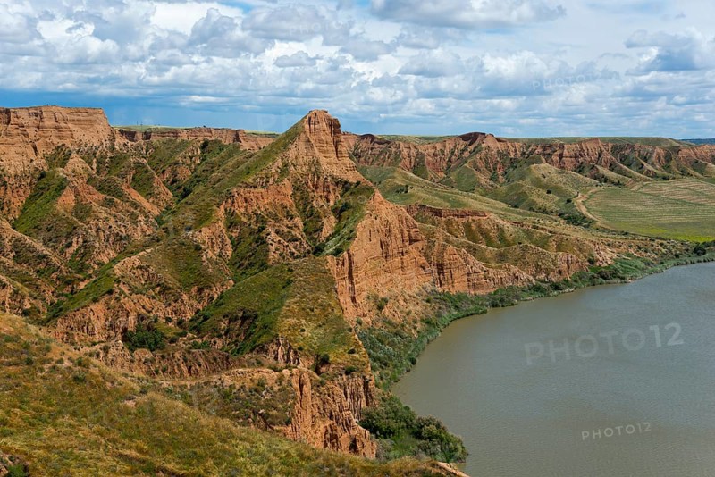 Eine weite Sicht auf einen grünen und braunen Canyon, der an einen ruhigen Fluss grenzt, Barrancas de Burujón, Burujon, río Tajo, Fluss Tajo, embalse de Castrejón, Stausee de Castrejon, Toledo, Kastilien-La Mancha, Spanien