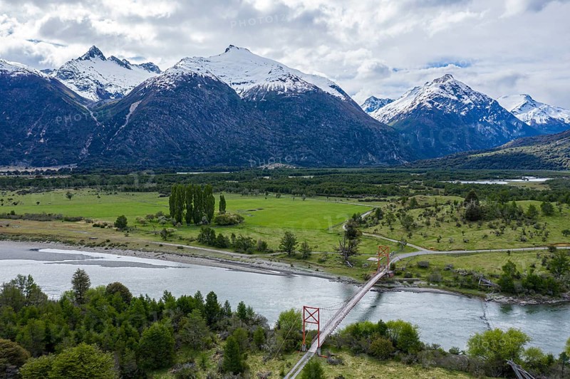 Old-style suspension bridge over river Rio Nadis south of Cochrane, snow-capped mountains at Rio Baker in the back, Patagonia, Chile, South America