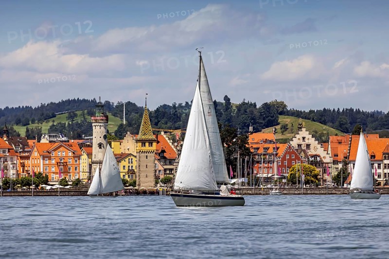 Harbour of Lindau, town view with lighthouse and man tower, sailing boat. Lindau, Lake Constance, Bavaria, Germany, Europe