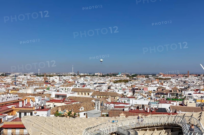 Sweeping views over the city with a hot air balloon on the horizon under a clear blue sky, Seville
