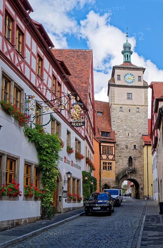 Historic half-timbered house, Hotel Tilman Riemenschneider, with blooming flower boxes in front of the windows in the eorgengasse, and behind it the White Tower in the old town of Rothenburg ob der Tauber. Rothenburg, Bavaria, Germany, Europe