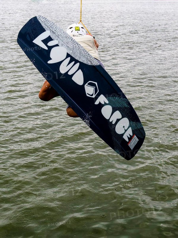 Young man with wakeboard at the jump start, water sports in the wakepark