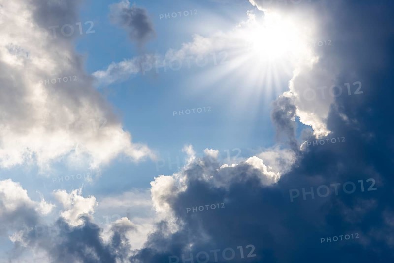 Rain clouds with sun shining through, rays of sunshine, blue sky