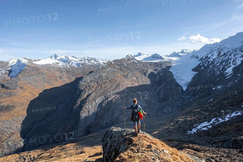 Mountaineer standing on a rock, surrounded by an impressive mountain landscape with snow-covered peaks in autumn View of Gurgler Ferner with summit Hochwilde and Falschungsspitze, Ötztal Alps, Tyrol, Austria, Europe
