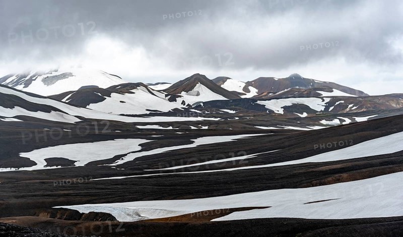 Dramatic volcanic landscape with mountains and snow, at Höskuldsskáli hut in Hrafntinnusker, Laugavegur trekking trail, Landmannalaugar, Fjallabak Nature Reserve, Suðurland, Iceland, Europe