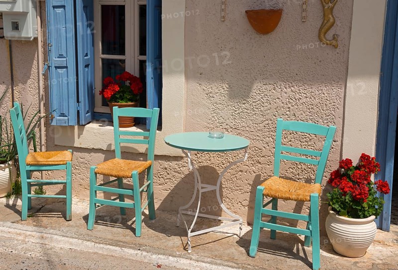 Cosy Mediterranean outdoor area with green chairs and blue shutters in front of a beige wall with red flowers, Agios Nikolaos, Mani, Messenia, Peloponnese, Greece, Europe
