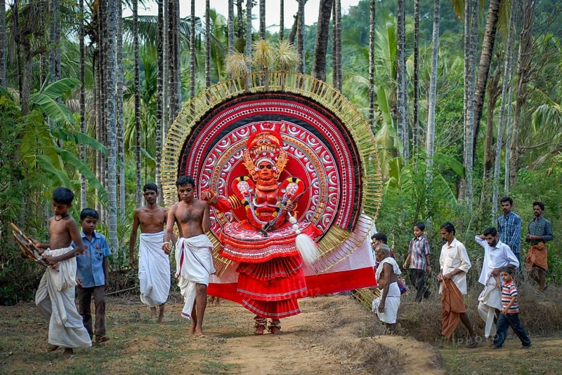 Colourful Theyyam being led through betel nut plantation, near Kasargod, North Kerala, Kerala, South India, India, Asia