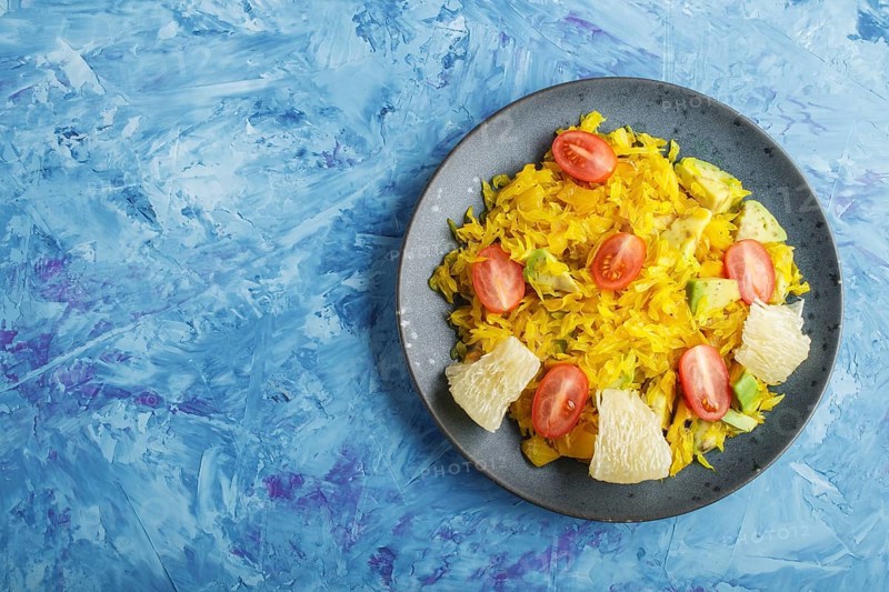 Fried pomelo with tomatoes and avocado on blue concrete background. Top view, copy space, myanmar food
