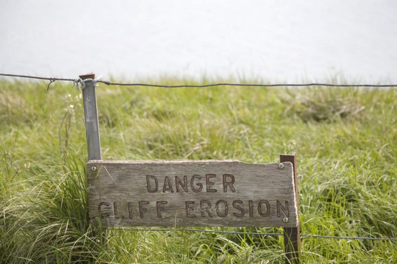 A wooden sign warning of the danger of cliff erosion at the top of the sheer cliffs at Beachy Head, East Sussex, England, United Kingdom, Europe