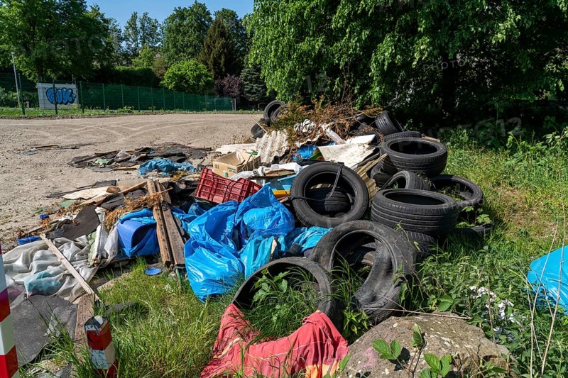 Illegally disposed waste, car tyres, building rubble, household waste, clothing, on a path next to a main road in Bochum, North Rhine-Westphalia, Germany, Europe
