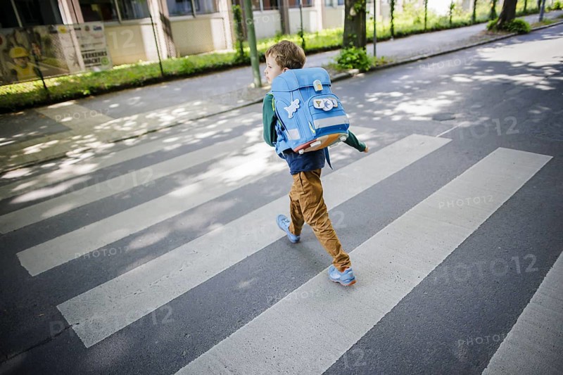 Symbol photo on the subject of schoolchildren in road traffic A six-year-old boy walks across the zebra crossing of a pedestrian crossing in front of a primary school with his school bag on his back. Berlin, 08.05.2024