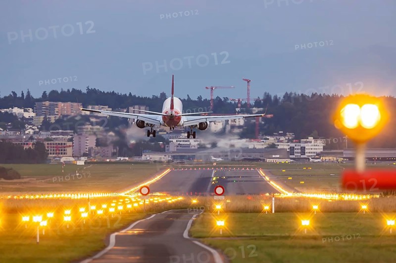 Helvetic Airways aircraft landing in the evening with illuminated runway. Zurich Airport, Switzerland, Europe