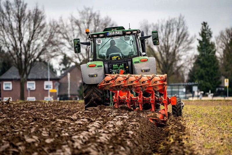 Tractor with a plough preparing the soil of a field for planting, Agriculture, Spring