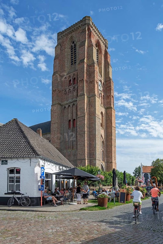 Tourists at sidewalk café and 13th century Gothic bell tower of Our Lady's Church in the village Lissewege near Bruges, West Flanders, Belgium, Europe