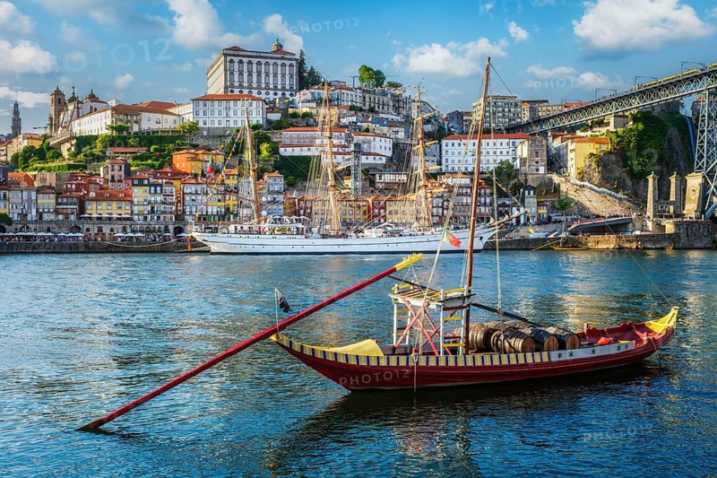 View of Porto city and Douro river with traditional boats with port wine barrels and sailing ship from famous tourist viewpoint Marginal de Gaia riverfront. Porto, Vila Nova de Gaia, Portugal, Europe