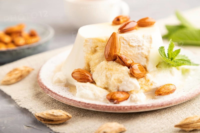 Ricotta cheese with honey and almonds on gray concrete background and linen textile. side view, close up, selective focus