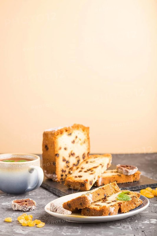 Homemade cake with raisins, dried persimmon and a cup of hot chocolate on a black and orange background. Side view, close up, copy space, selective focus
