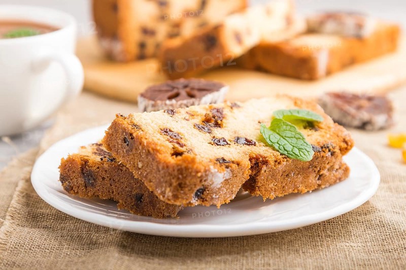 Homemade cake with raisins, dried persimmon and a cup of hot chocolate on a gray concrete background and linen textile. Side view, close up, selective focus