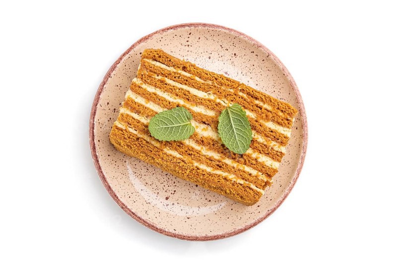Homemade honey cake with milk cream and mint isolated on white background. Top view, close up, flat lay