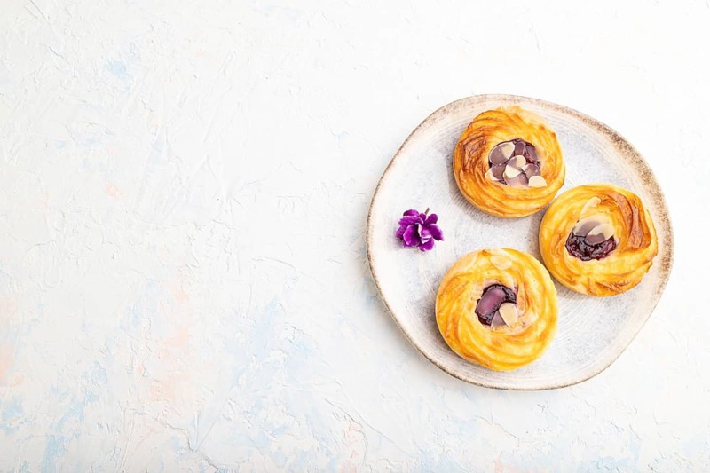 Small cheesecakes with jam and almonds with cup of coffee on a white concrete background. top view, flat lay, copy space