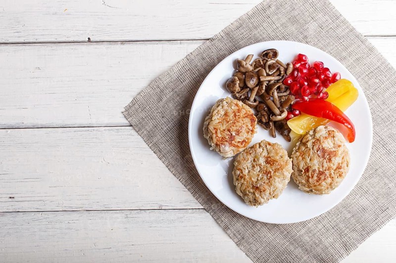 Meatballs with rice mushrooms, sweet peppers and pomegranate seeds on white wooden background. top view, copy space